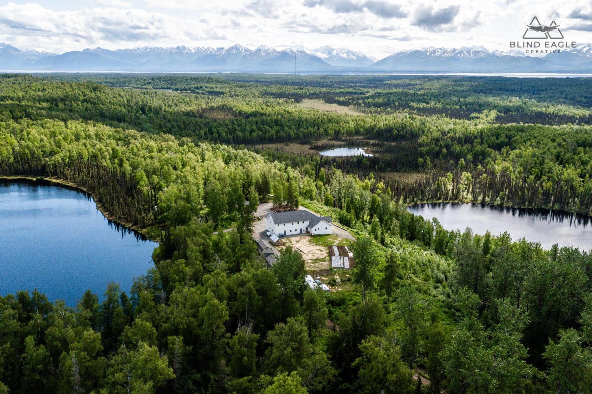 Aerial drone view of a remote off grid Alaska home on secluded acreage with wide Chugach Mountain views near Anchorage and surrounding communities.